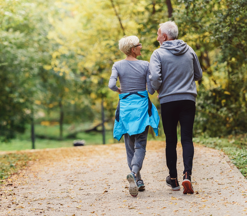 Cheerful active senior couple jogging in the park. Exercise toge